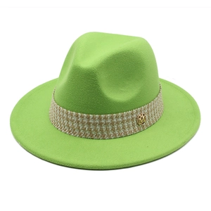 Detail of wool felt fedora in bright green featuring a plaid band and golden metal M badge
