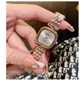 Close-up of rose gold square quartz watch with metal mesh band on female wrist