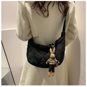 Detailed shot of black quilted crescent bag featuring a cute bunny plush charm accessory