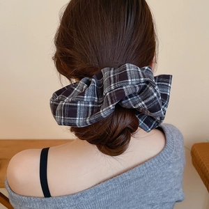 Detail showing the classic plaid fabric scrunchie styled in a soft bun hairstyle