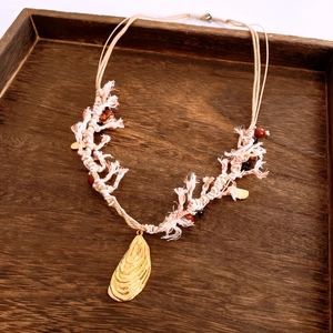 Detail of bohemian hand-woven pink cotton rope necklace with a gold shell pendant