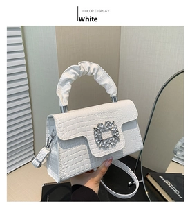 Detail of white crocodile pattern handbag with large crystal buckle and ruched handle