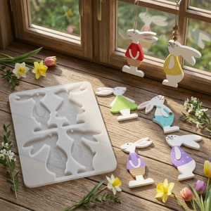 Silicone rabbit charm mold with colorful resin bunny pendants on a bright wooden window sill