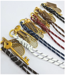 Detailed close-up of woven keychains featuring gold tennis racket and abacus charms