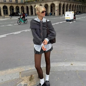 Schulterfreier dunkelgrauer Strickpullover mit Streifenhemd und Faltenrock Straßenlook