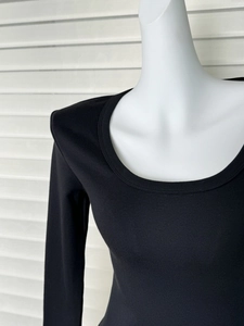 Dettaglio della maglia nera a maniche lunghe con scollo a U e trama a costine