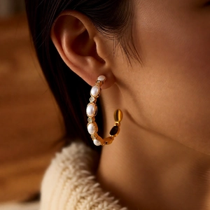 Detailed view of 18K gold plated C-shaped hoop earrings with pearls and crystals on a model