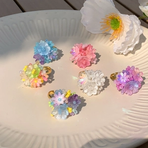 Detailed close-up of colorful beaded floral rings on a white textured ceramic dish