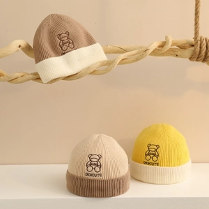 Détail de bonnets tricotés pour bébé avec broderie ours et texture bicolore