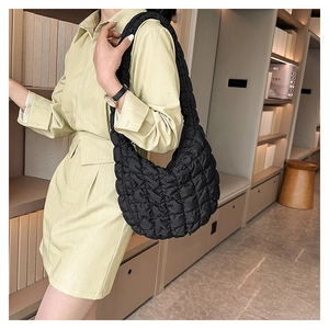 Detailed view of black quilted puff shoulder bag texture on model in soft lighting