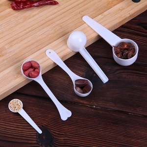 Set of four white plastic measuring spoons for kitchen spices on a rustic wooden background
