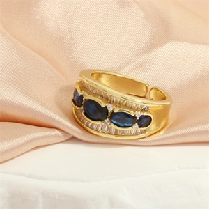 Detail of 18K gold ring featuring three blue oval stones and white rectangular crystals
