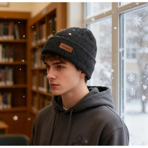 Detailed close-up of dark grey knitted beanie with brown leather logo patch