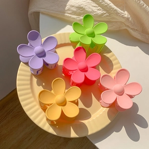 Floral hair claws for girls in matte macaron colors arranged on a yellow plate
