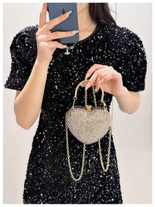 Detail view of heart-shaped evening bag featuring iridescent rhinestones and metal handle