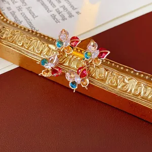 Vintage gold butterfly earrings with colorful zircon crystals on a retro background