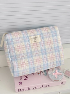 Detailed close-up of colorful checkered makeup bag with heart quilting and fabric label