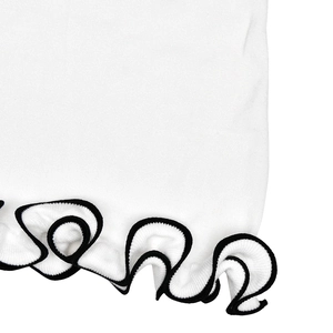 Detailed close-up of white knitted dress hem featuring black contrast ruffle edges