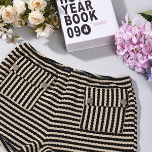 Detail van gebreide korte broek met strepen, hoge taille en zilveren knoopzakken