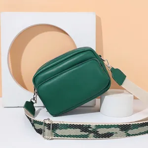 Borsa a tracolla minimalista in pelle verde smeraldo con ampia tracolla in tessuto operato