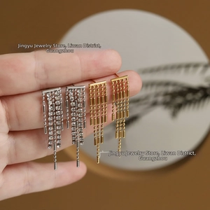 Detail of long tassel earrings in gold and silver finish with sparkling zircon accents