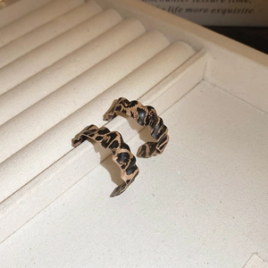 Macro shot of wave-shaped leopard print earrings on a premium beige jewelry display box