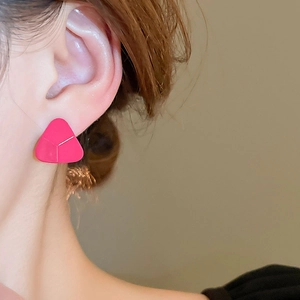 Gros plan d'une boucle d'oreille triangle géométrique rose pour un style minimaliste