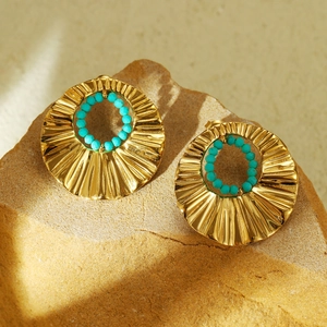 Macro view of gold stainless steel earrings with turquoise beads and wave texture