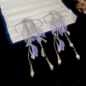 Detail of long tassel earrings with purple resin leaves and sparkling rhinestones