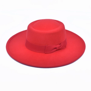 Close-up of bright red wool boater hat featuring a flat top and matching ribbon bow