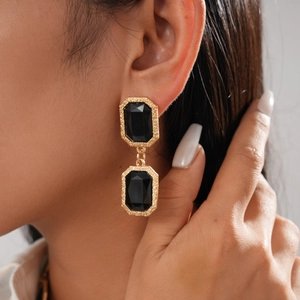 Gros plan d'une femme portant des boucles d'oreilles vintage noires et dorées octogonales