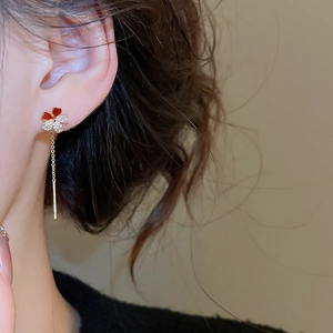 Close-up of elegant gold flower drop earrings with red petals and zircon crystals