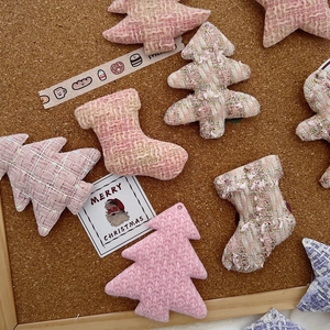 Detailed view of pink tweed Christmas tree and star ornaments on cork background