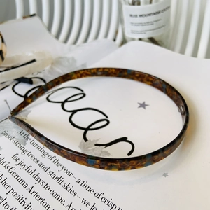 Detail of tortoise shell acetate headband placed on an open magazine for a retro look