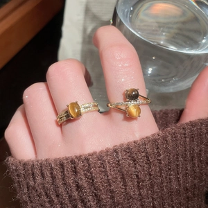 Detail view of gold-plated tiger eye stone rings with micro-set zircons on hand
