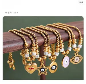 Detail of five gold-plated bracelets featuring evil eye charms on a wooden jewelry display stand
