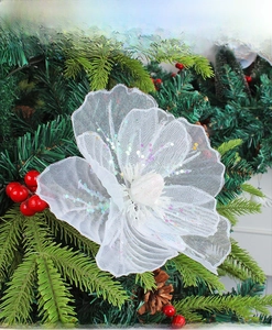 Close-up of white mesh Christmas flower with sequins on tree branches with red berries