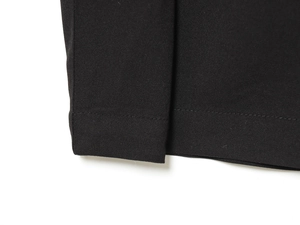 Detail shot of black twill pleated pants showcasing fine stitching and fabric texture