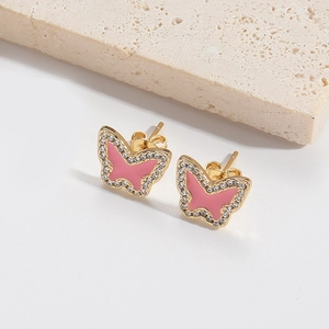 Vue macro de boucles d'oreilles papillon roses avec bordure dorée et zircons blancs