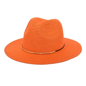 Close-up of bright orange straw panama hat with a stylish golden metal decorative band