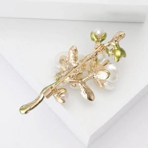 Elegant gold plum blossom branch brooch with white pearls and green enamel on white stand