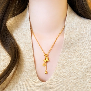Golden Chinese zodiac horse pendant necklace with coin charms on a model wearing knitwear