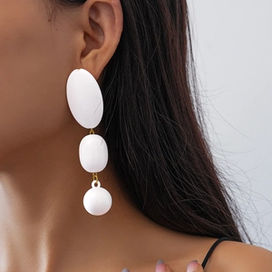 Détail de boucles d'oreilles en perles acryliques blanches et maillons dorés sur modèle