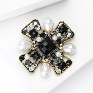 Baroque cross brooch with black crystals and white teardrop pearls on white pedestal