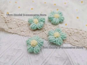 Detailed macro view of four handmade crochet yarn flowers in light green and yellow