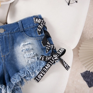 Dettaglio di pantaloncini di jeans a vita alta con orlo a frange e lacci laterali