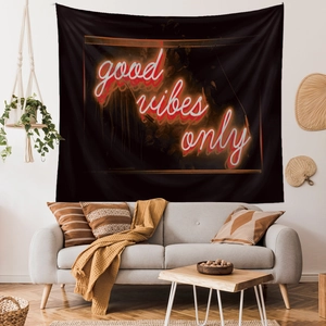 Detail of black wall tapestry featuring neon red and white Good Vibes Only text in a room