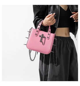 Pink gothic punk handbag with silver spikes and cross pendant on a black jacket