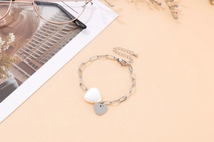 Détail du bracelet à maillons avec pendentifs en forme de cœur argenté et nacre blanche polie