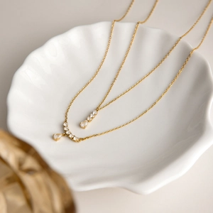 Detail van 18K gouden ketting met fonkelende druppel-zirkonia op een schelpenbordje